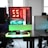 A modern gaming setup is displayed on a desk with multiple computer monitors and an open gaming PC tower. The tower is illuminated with red and green LED lights, showcasing a 'GeForce RTX' graphics card. A gaming mouse rests on a mousepad with glowing edges, and there is a keyboard with vibrant backlighting. The room appears well-lit with visible windows in the background.