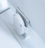 A white, sleek, vertical gaming console placed beside a large, slim monitor. The setting exudes minimalism with a focus on modern technology design.