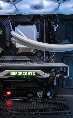 A high-end gaming or performance PC interior equipped with RGB lighting and multiple cooling fans. The graphics card prominently displayed is a GeForce RTX model, with branding visible. The setup includes neatly managed cables and a liquid cooling system.